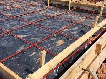 Foundation preparation with rebar grid and wooden formwork for concrete pouring.