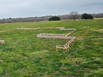 Wooden framework laid out on a grassy field for construction.