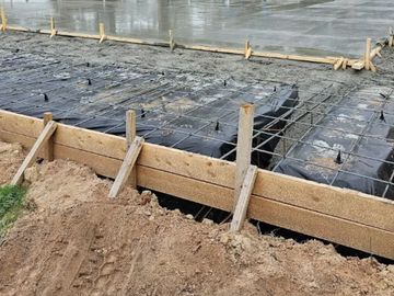Concrete slab foundation under construction with rebar and formwork.