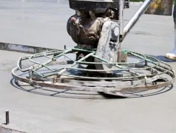 Concrete power trowel smoothing a freshly poured concrete surface.