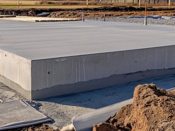 Freshly poured concrete foundation slab at a construction site.