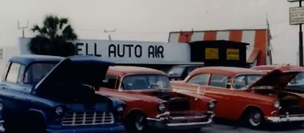 Vintage cars with open hoods at a classic auto repair shop.