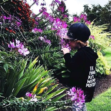 Young kind, gentle boy in stylish outfit, smelling flowers in prince edward island