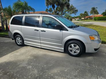 Silver minivan parked on a driveway on a sunny day.
