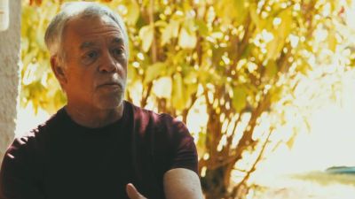 Older man sitting and talking outdoors.