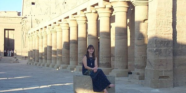 Woman sitting in front of ancient pillars.