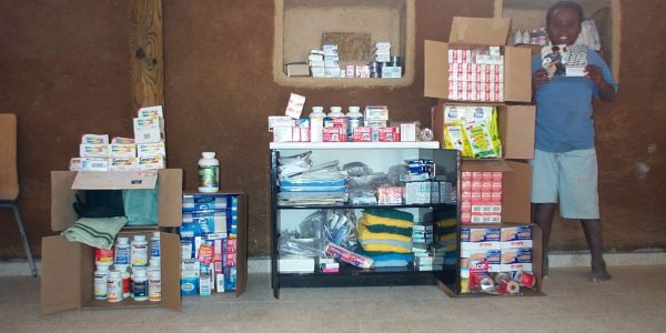 Shelves filled with various medical supplies and a child holding medicine box.