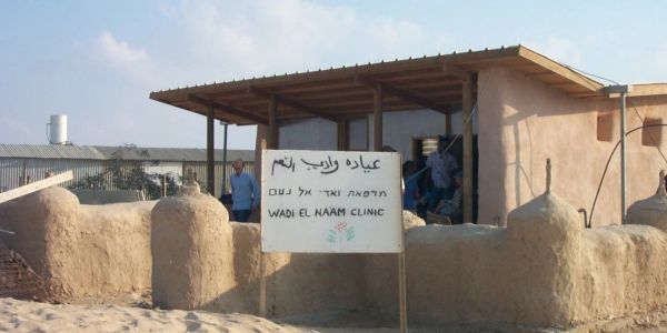 Small clinic building with a sign in multiple languages.
