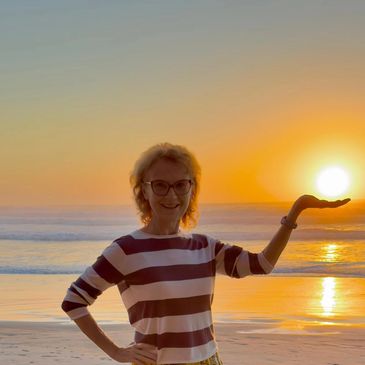 Woman holding the sun at sunset on the beach.