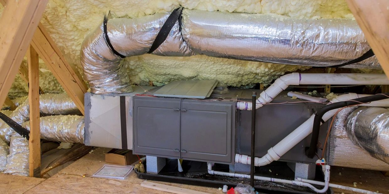 A modern HVAC system installed in an attic with insulated ductwork and spray foam insulation.