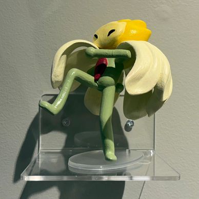 A playful figurine of a green character with yellow hair and white wings on a clear display stand.
