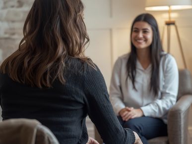 Two women engaged in a friendly conversation in a cozy setting.