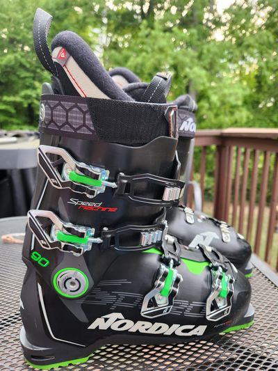 Black and green Nordica ski boots on a table.