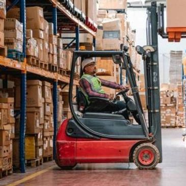 Worker operating a forklift in a warehouse filled with boxes.