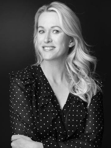 Smiling woman with polka dot blouse posing against a black background.