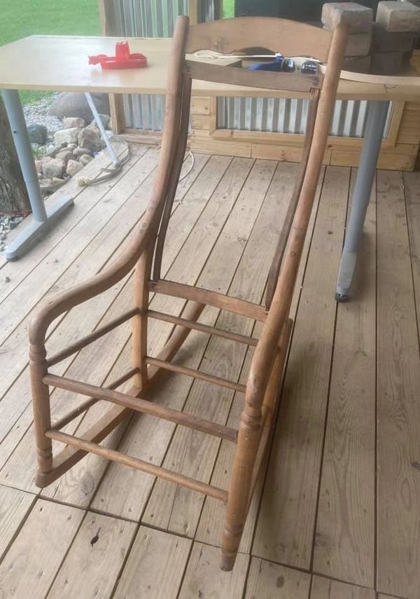 Wooden chair being repaired on a wooden deck with a table in the background.