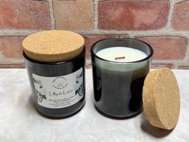 Two black glass candles with cork lids on a marble surface.