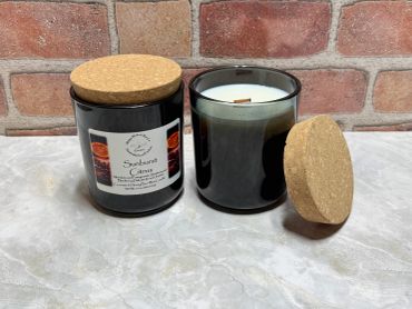 Two black glass candles with cork lids, one labeled Sunburst Citrus.