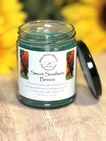Close-up of a Sweet Southern Breeze candle jar with yellow flowers in the background.