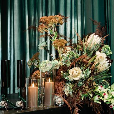 Elegant floral arrangement with candles and dark background.