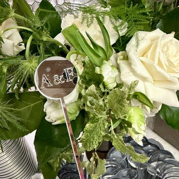 White roses and green foliage with a silver A&F sign.