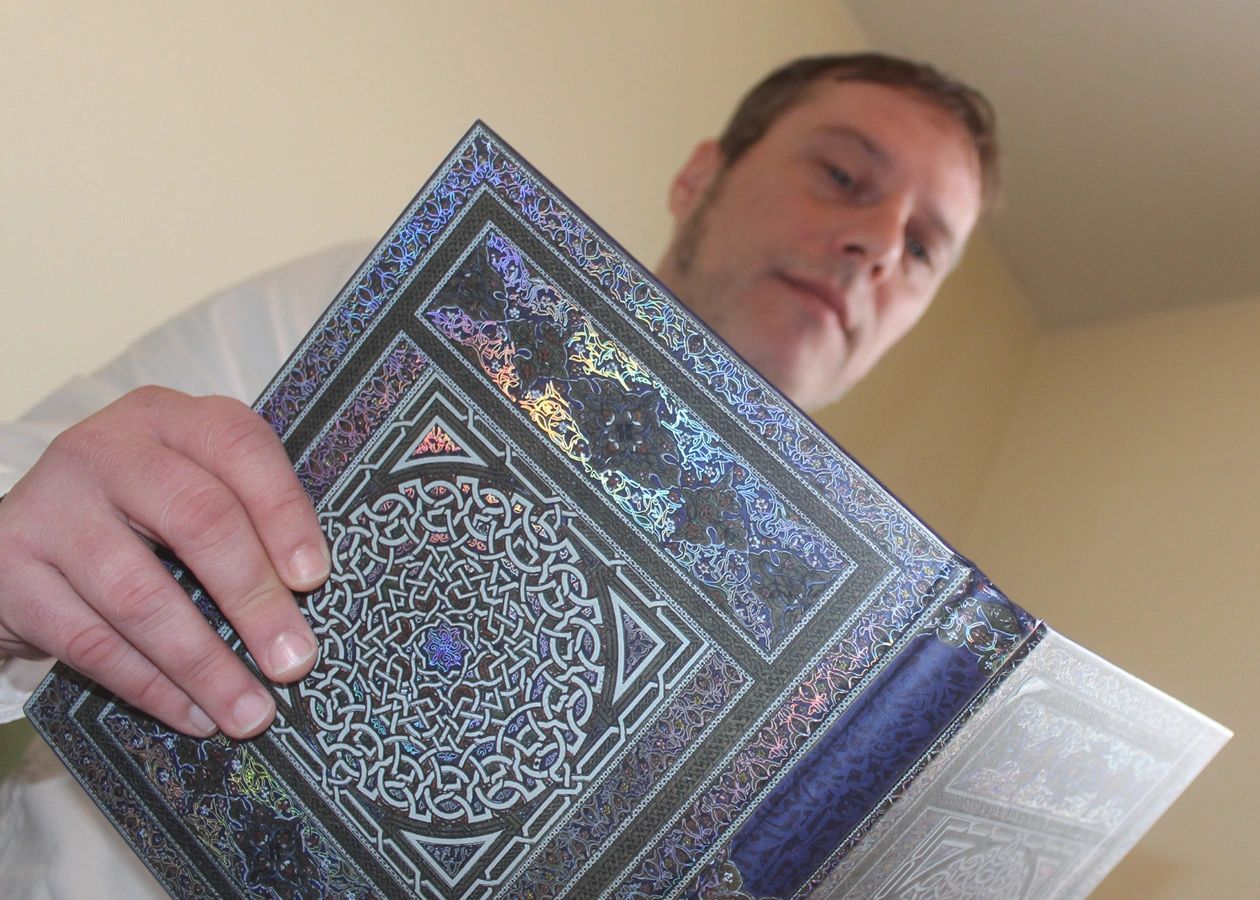 Man holding an ornate, decorative book with intricate patterns.