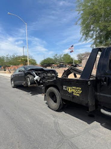 Tow truck loading a damaged car after an accident on a sunny day.