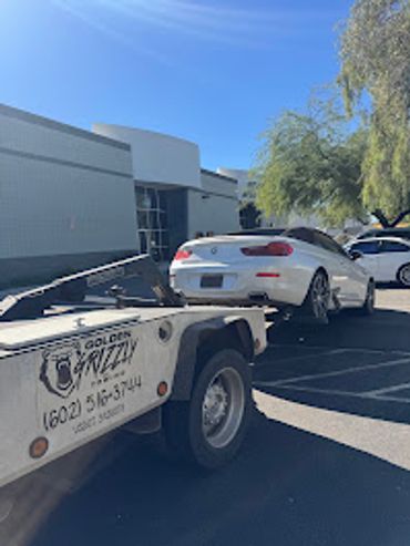 A white sports car being towed by Golden Grizzly towing service.