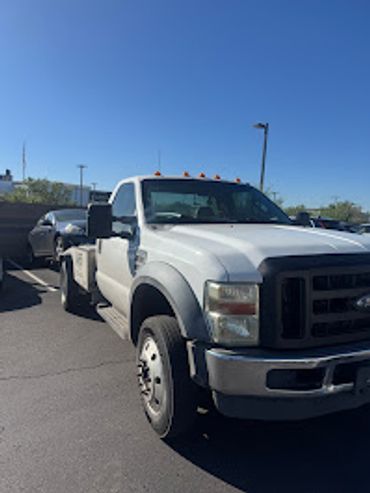 A white flatbed truck parked in a sunny lot.