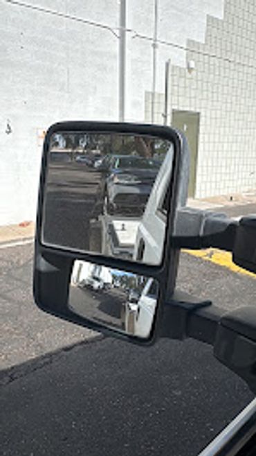 Side mirror of a vehicle showing street reflection.
