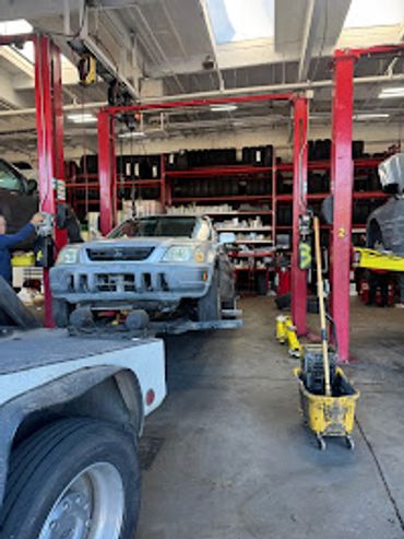 A car lifted on a red hydraulic lift in an auto repair shop.