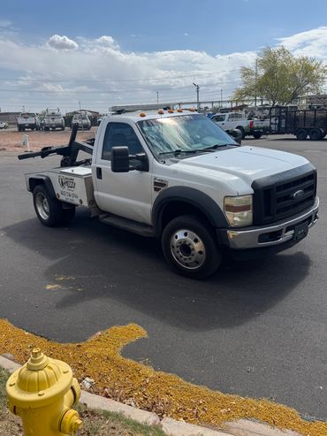 White Ford F-450 tow truck parked near a yellow fire hydrant.