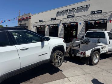 White Jeep Compass being towed at an auto service shop.