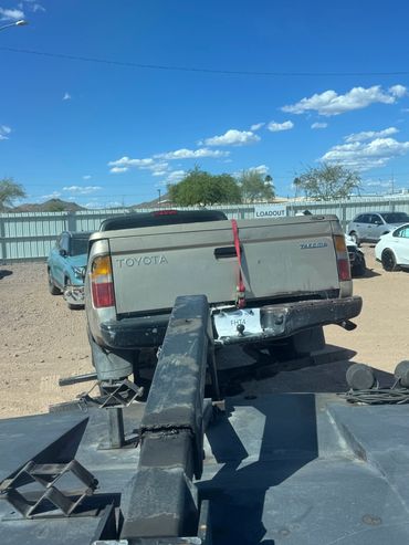Old Toyota Tacoma truck being towed on a sunny day.