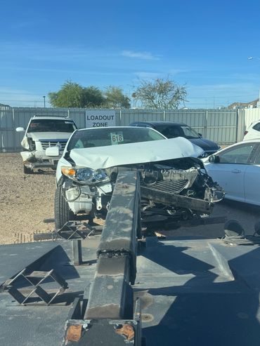 Damaged cars in a loadout zone under a clear blue sky.