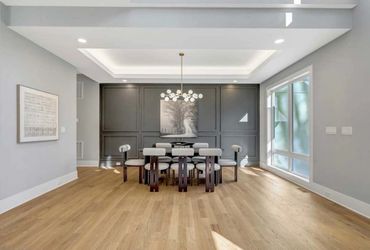Modern dining room with gray walls, wooden floor, and unique chairs.
