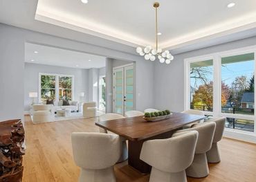 Modern dining and living area with large windows and wooden floors.