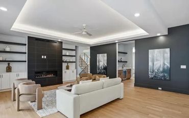 Modern living room with fireplace, light furniture, and dark accent walls.