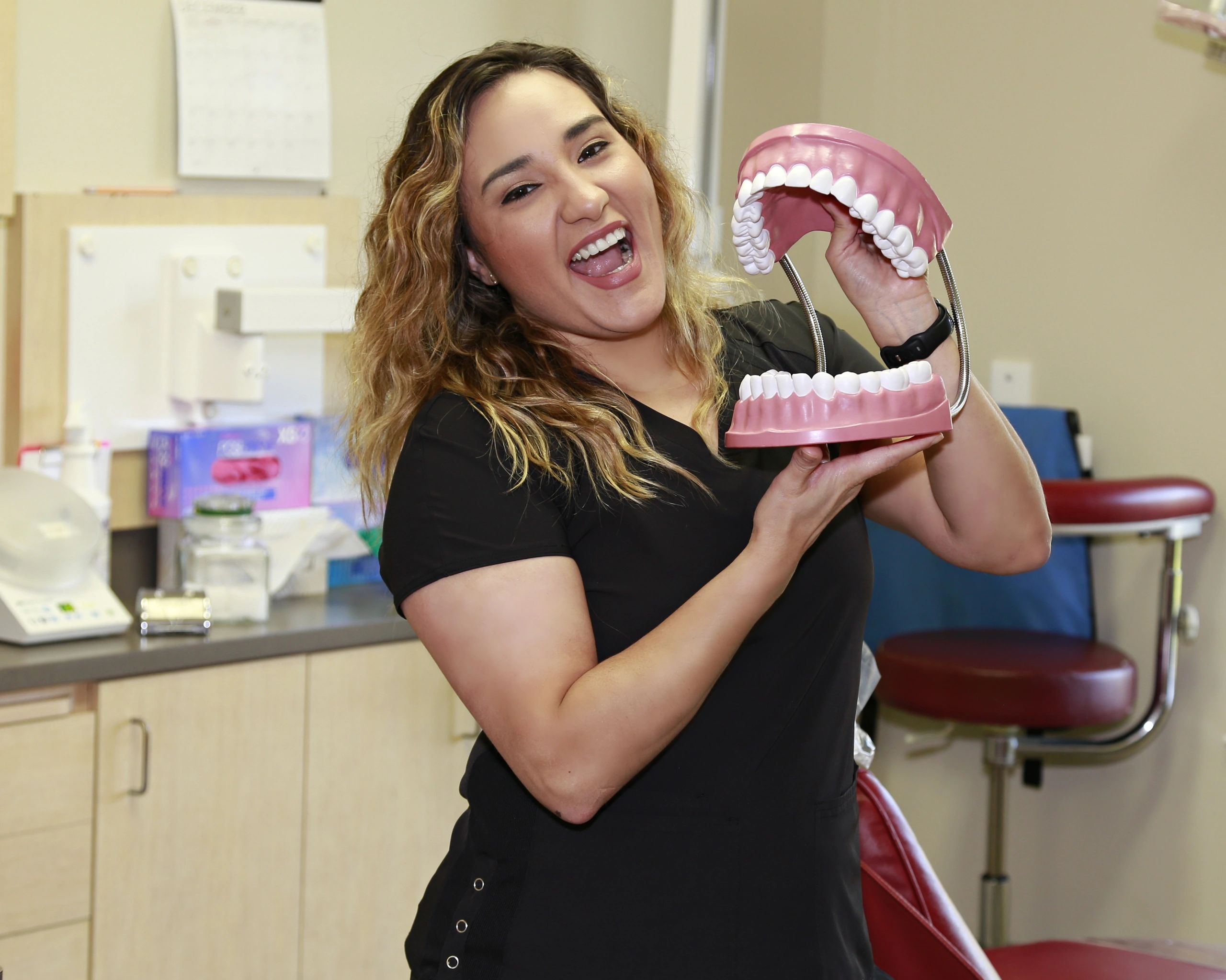 Dental assistant holding and mocking a large mouth model.
