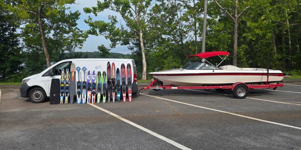 Boat and water skis parked near a white van.