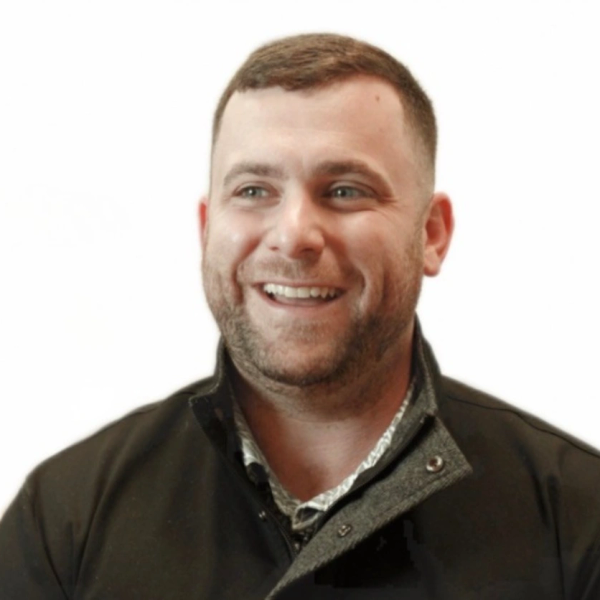 Smiling man with short hair and beard wearing a dark jacket.