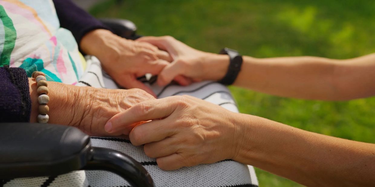 Close-up of an elderly and a younger hand holding each other.