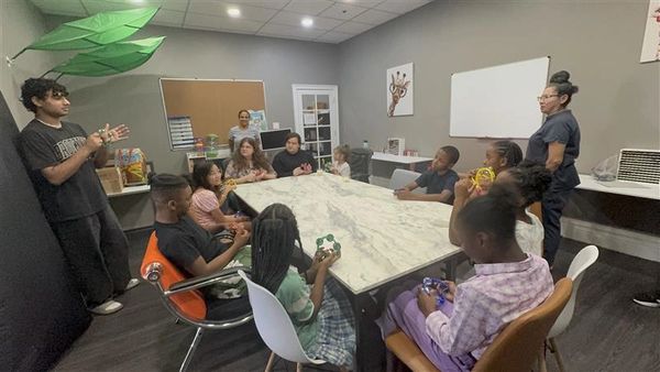 Group of children and adults gathered around a table in a classroom setting.