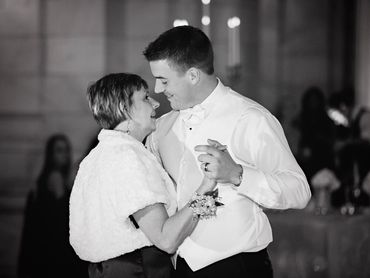 A joyful mother and son share a dance at a wedding reception.
