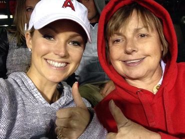 Two women smiling and giving thumbs up at a sports event.