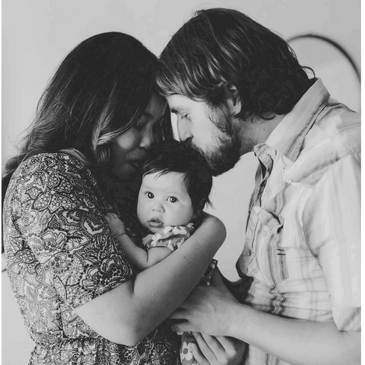 A tender moment of parents with their baby in black and white.
