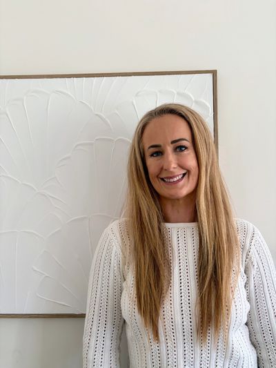 Smiling woman with long blonde hair in white sweater.