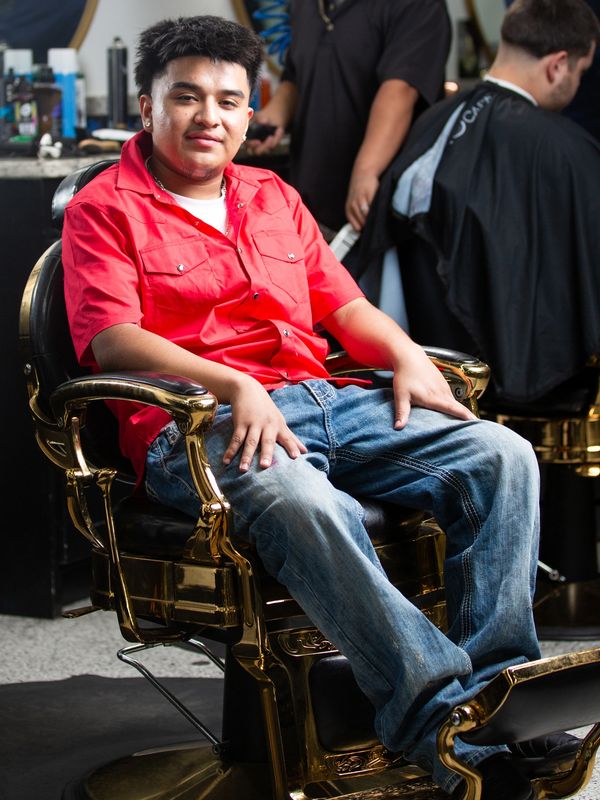 Young man sitting relaxed in a vintage barber chair at a barbershop.
