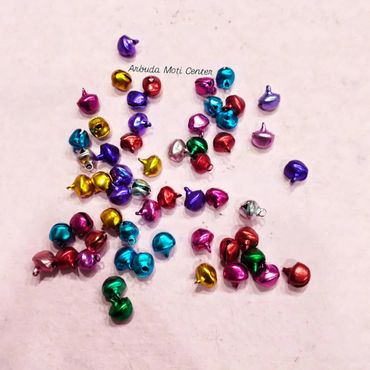 Colorful small metallic bells scattered on a light surface.