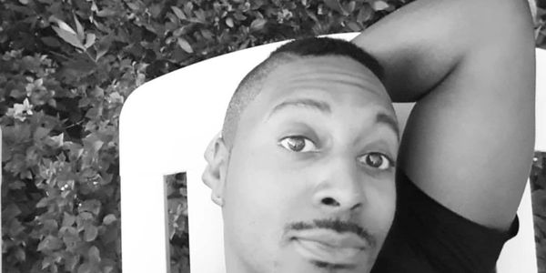 Black and white selfie of a man relaxing on a chair outdoors.